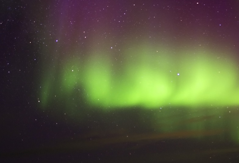 Vertical magnetic rays rising into violet nitrogen glow.